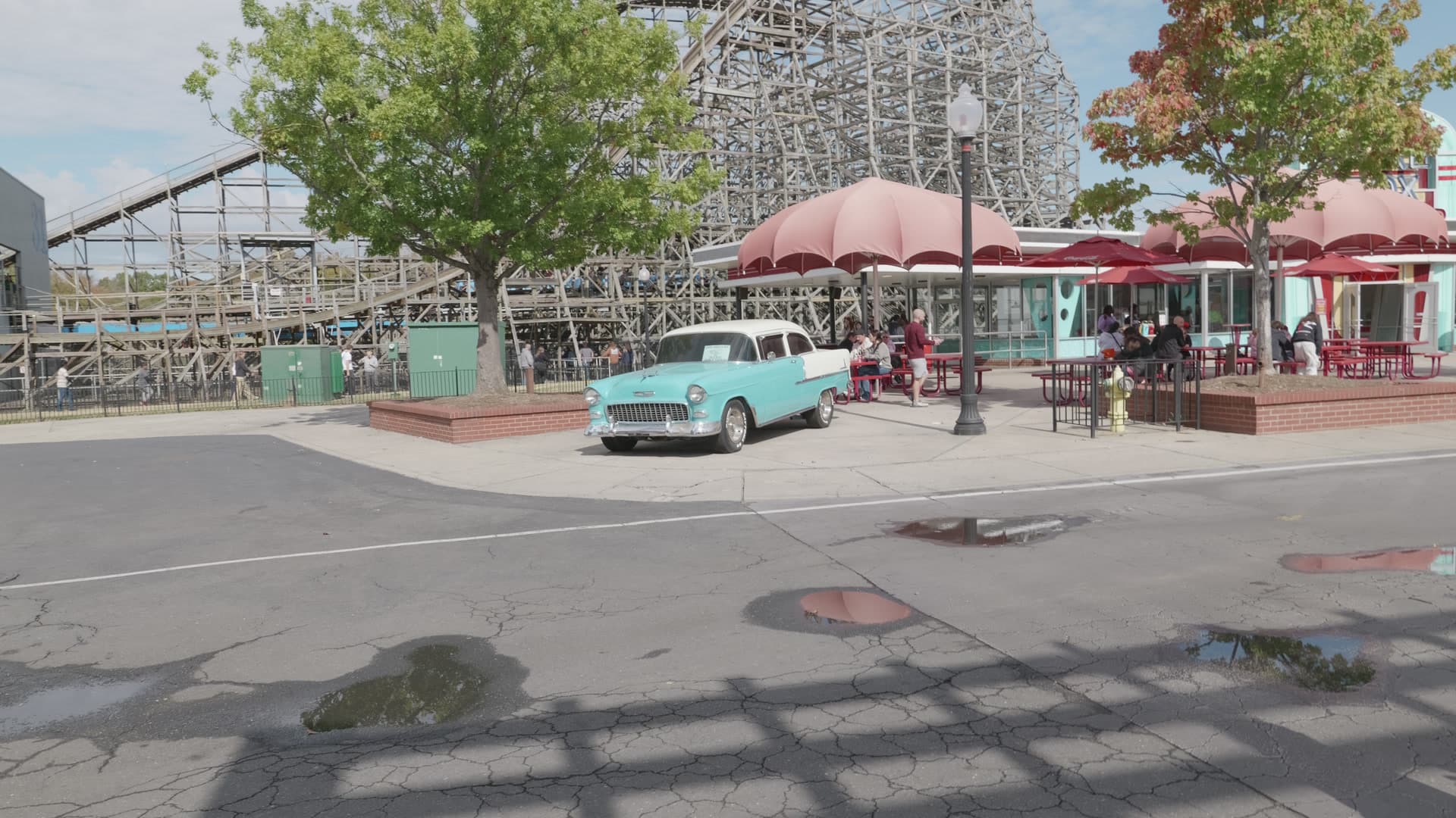 A turquoise car outside a diner with wooden coaster track behind it at Carowinds